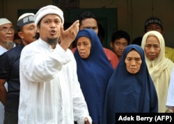 Ulama Dzulkarnain (kiri) meneriakkan slogan-slogan di samping Tariyem (kedua dari kanan) ibu dari terpidana pelaku bom Bali 2002 Amrozi dan Mukhlas, dan dua saudara perempuan (belakang) dalam kunjungan mendukung tiga pelaku bom Bali. (Foto: AFP)
