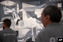 Dua pria berjalan melewati lukisan "Guernica" Pablo Picasso di Museum Reina Sofia di Madrid, Spanyol, Senin, 12 September 2022. (AP/Andrea Coma)