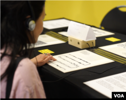 Pengunjung dapat mendengarkan rekaman suara lewat headphone sambil melihat caption secara visual maupun dengan huruf Braille (courtesy VOA Indonesia)