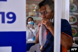 Seorang pria meniup kantong nafas untuk tes GeNose C19 untuk skrining virus corona di Bandara Internasional Sultan Iskandar Muda di Blang Bintang, pada 25 April 2021. (Foto: AFP/CHAIDEER MAHYUDDIN)