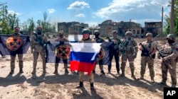 Yevgeny Prigozhin, pemimpin perusahaan militer Grup Wagner saat memegang bendera nasional Rusia di depan tentaranya di Bakhmut, Ukraina. (Foto: via AP)