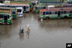 Penumpang mengarungi terminal bus yang terendam banjir akibat hujan lebat di Lahore, Pakistan, Rabu, 5 Juli 2023. (AP/K.M. Chaudary)