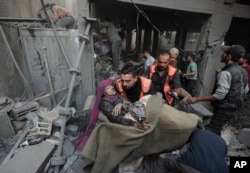 Tim penyelamat Palestina mengevakuasi seorang perempuan terluka yang ditemukan di bawah reruntuhan rumah yang hancur menyusul serangan udara Israel di kamp pengungsi Khan Younis, Jalur Gaza selatan, 18 November 2023. (Foto: AP)