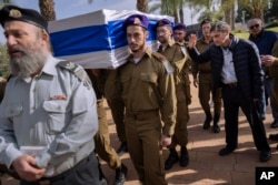 Yoram (kanan), ayah dari tentara Israel Letnan Yaacov Elian, mengucapkan selamat tinggal saat para tentara lainnya mengusung peti jenazah putranya untuk dimakamkan di pemakaman militer di Tel Aviv, Israel, Jumat, 22 Desember 2023. (Foto: Oded Balilty/AP Photo)