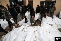 Petugas medis dan sukarelawan menyiapkan jenazah yang tewas dalam serangan Israel semalaman di kamp pengungsi Al-Maghazi, menjelang pemakaman massal di RS Al-Aqsa di Deir Al-Balah, di Jalur Gaza selatan, pada 25 Desember 2023. (Foto: AFP)