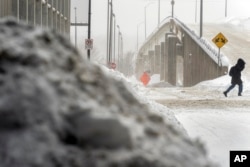 Seorang perempuan berjalan melewati salju di pusat Kota Des Moines, Iowa, Sabtu, 13 Januari 2024. (Foto: AP) ​