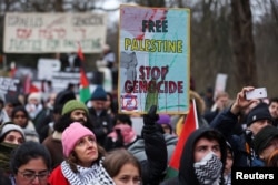 Seorang demonstran pro-Palestina memegang plakat saat melakukan protes di dekat Mahkamah Internasional (ICJ) di Den Haag, Belanda, 11 Januari 2024 (Foto: Reuters)