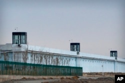 FILE - Seseorang berdiri di menara di perimeter Pusat Penahanan Nomor 3 di Dabancheng, Daerah Otonomi Uyghur Xinjiang, China barat, 23 April 2021.