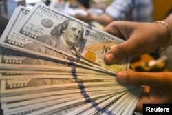 Seorang karyawan menunjukkan uang kertas dolar AS di money changer di Jakarta, 24 April 2018. (Foto: Antara Foto/Hafidz Mubarak/via REUTERS)