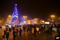Orang-orang berkumpul pada Malam Tahun Baru di sekitar pohon Natal di Lapangan Lenin yang didekorasi untuk perayaan liburan di Donetsk, Ukraina timur, Jumat, 31 Desember 2021. (Foto: AP)