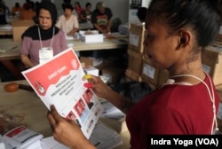 Seorang relawan memeriksa lembar surat suara untuk pemilihan calon presiden dan wakil presiden di Gudang KPU Kotamadya Jakarta Timur, Kamis, 11 Januari 2024. (Foto: Indra Yoga/VOA)