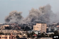 Gambar yang diambil dari Rafah di Jalur Gaza selatan menunjukkan asap membubung di atas gedung-gedung di Khan Yunis dari kejauhan, menyusul pemboman Israel pada 5 Februari 2024. (Foto: AFP)