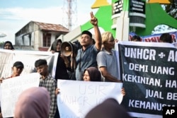Para pengunjuk rasa memegang poster saat mengelar demonstrasi di Sabang, Aceh, Senin, 18 Desember 2023. (Foto: AP)